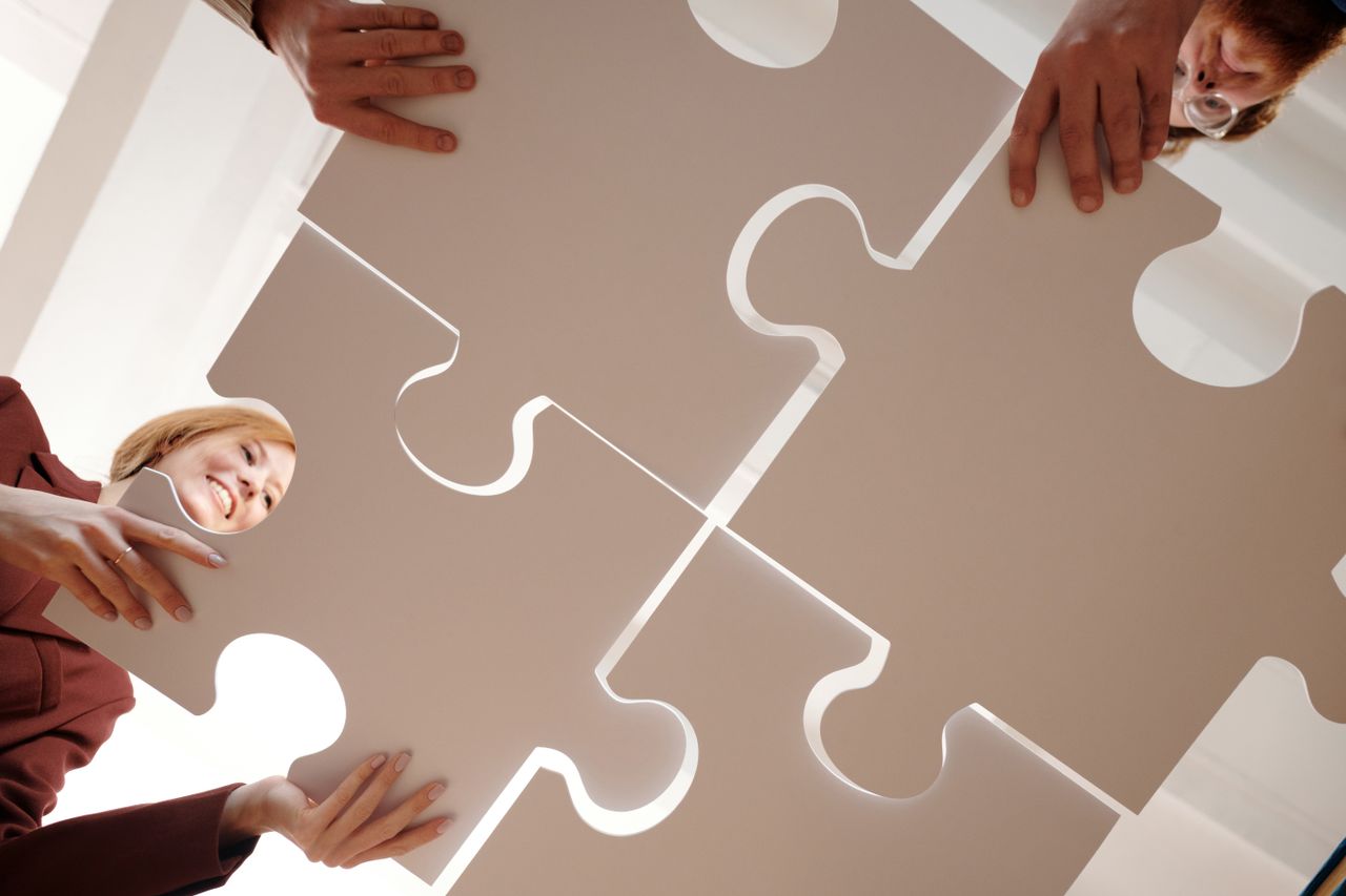 Low angle view of diverse team assembling large puzzle pieces, symbolizing unity and cooperation